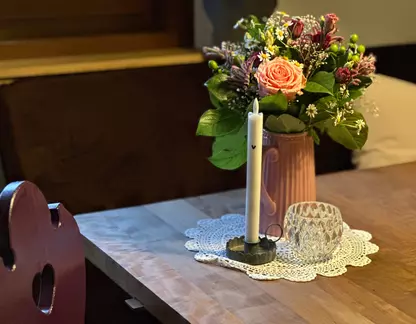 Blumenstrauß und Kerze auf Holztisch