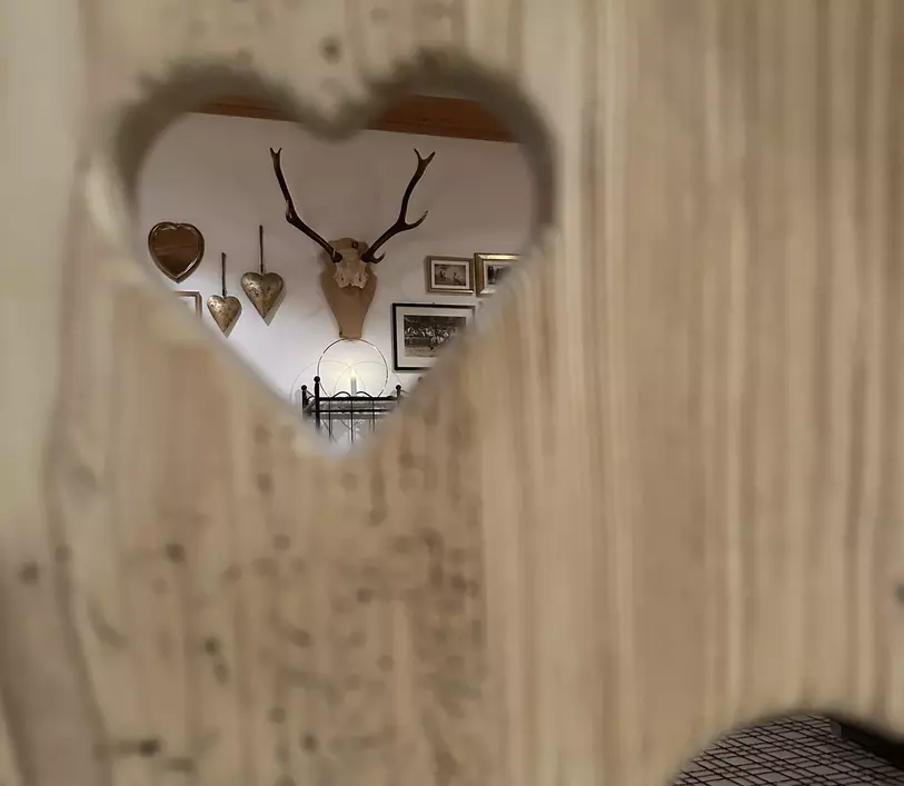 Blick auf Wanddekoration durch herzförmigen Ausschnitt in Holztür